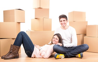 Happy couple with boxes moving into new home apartment